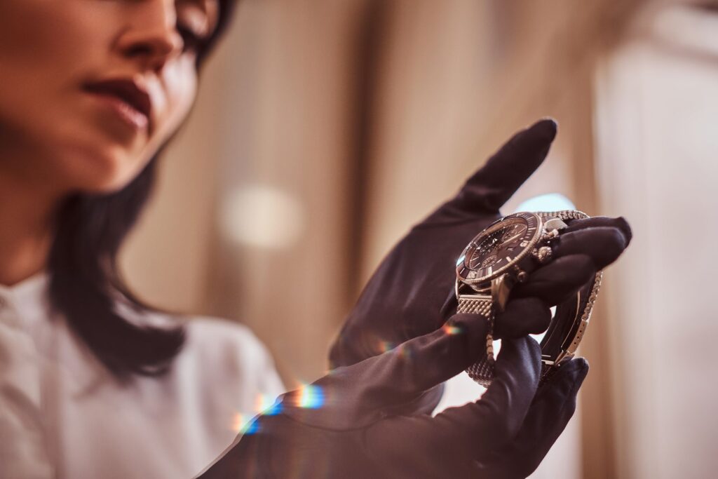 Woman holding an expensive watch using gloves
